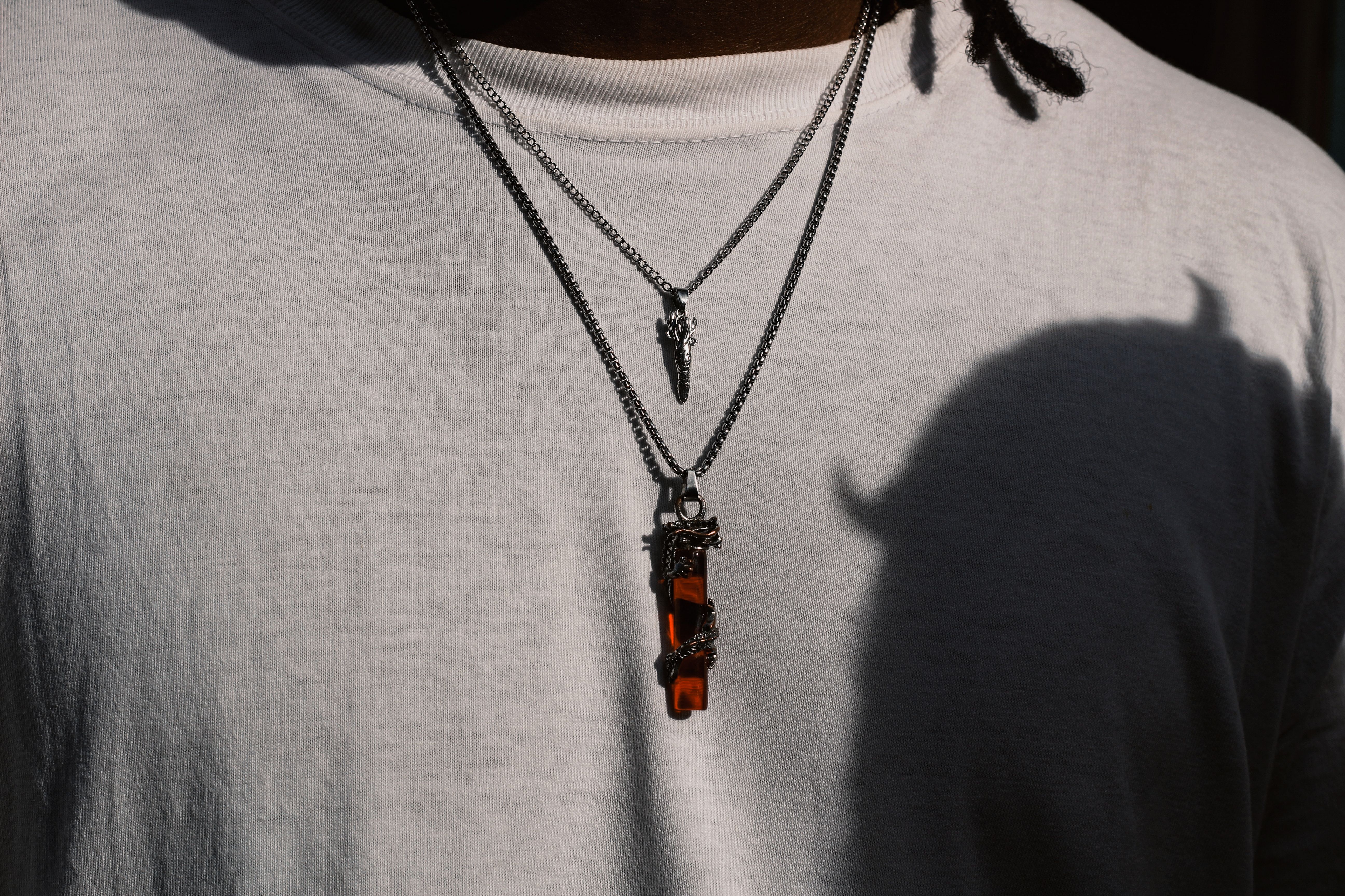A man wearing layered necklaces of different lengths including a 16-inch base chain
