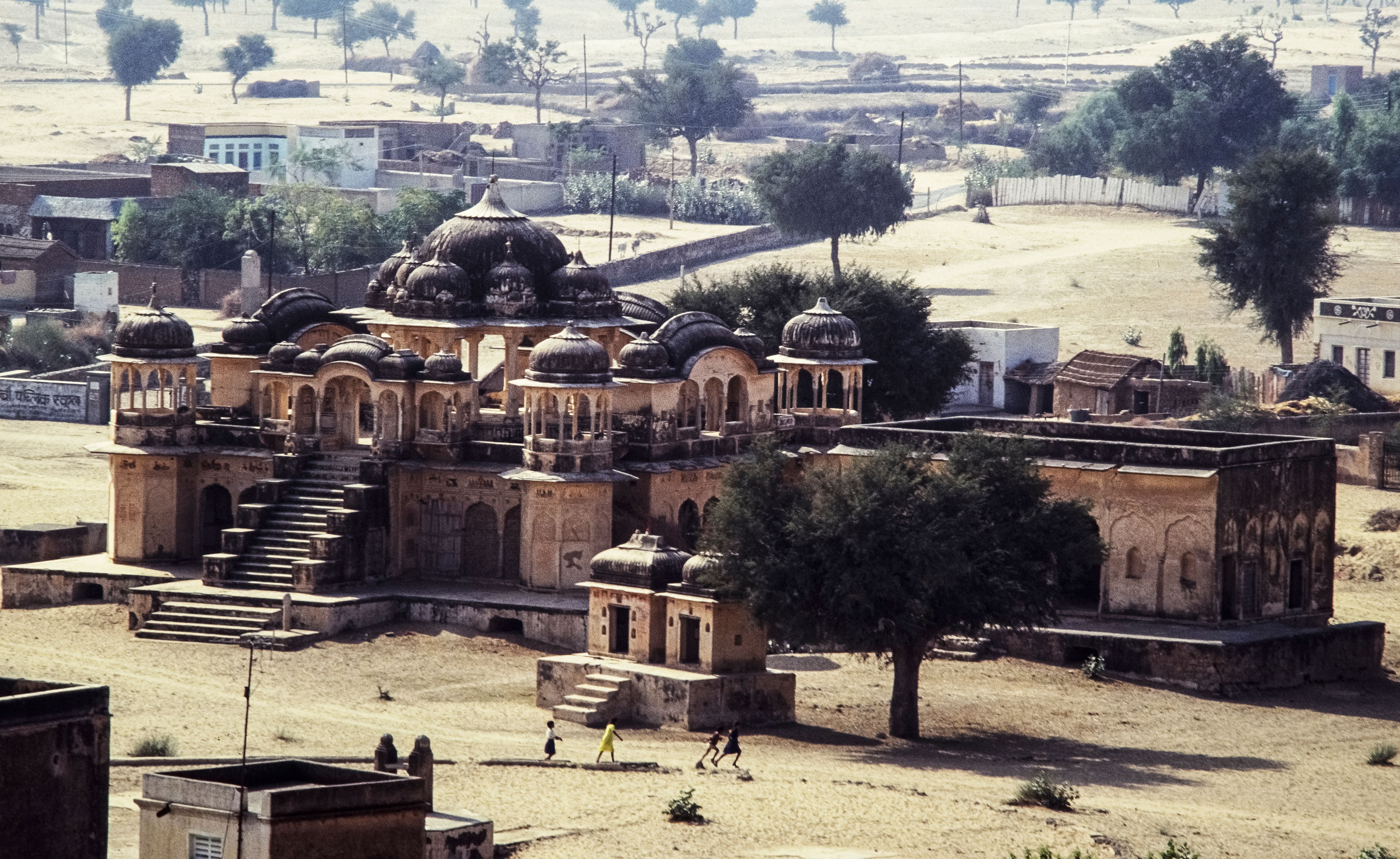Aerial view of a historic palace in Rajasthan, India, showcasing architectural beauty and rural surroundings.