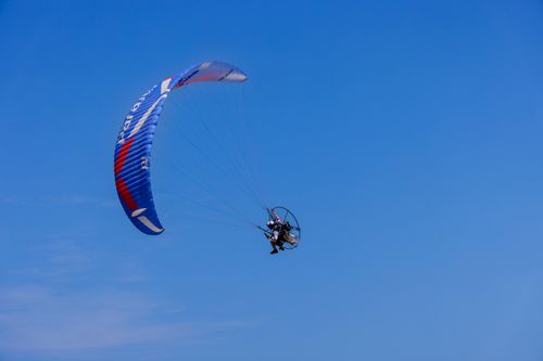 Free A person flies a paramotor under a clear blue sky in Sam Roi Yot, Thailand. Stock Photo