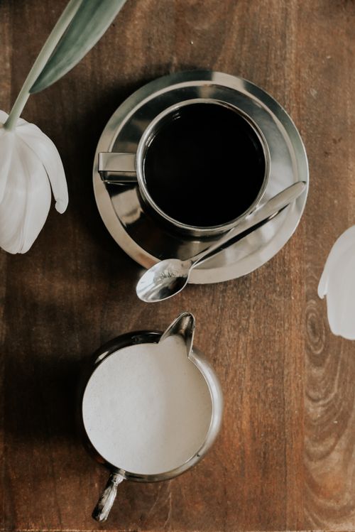 Free A stylish coffee scene with a cup, milk jug, and tulips on a wooden table. Stock Photo