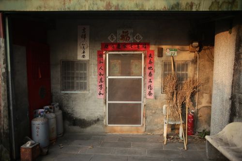 Free An entrance to a traditional Asian house with red decorative banners and broomsticks, exuding a rustic charm. Stock Photo