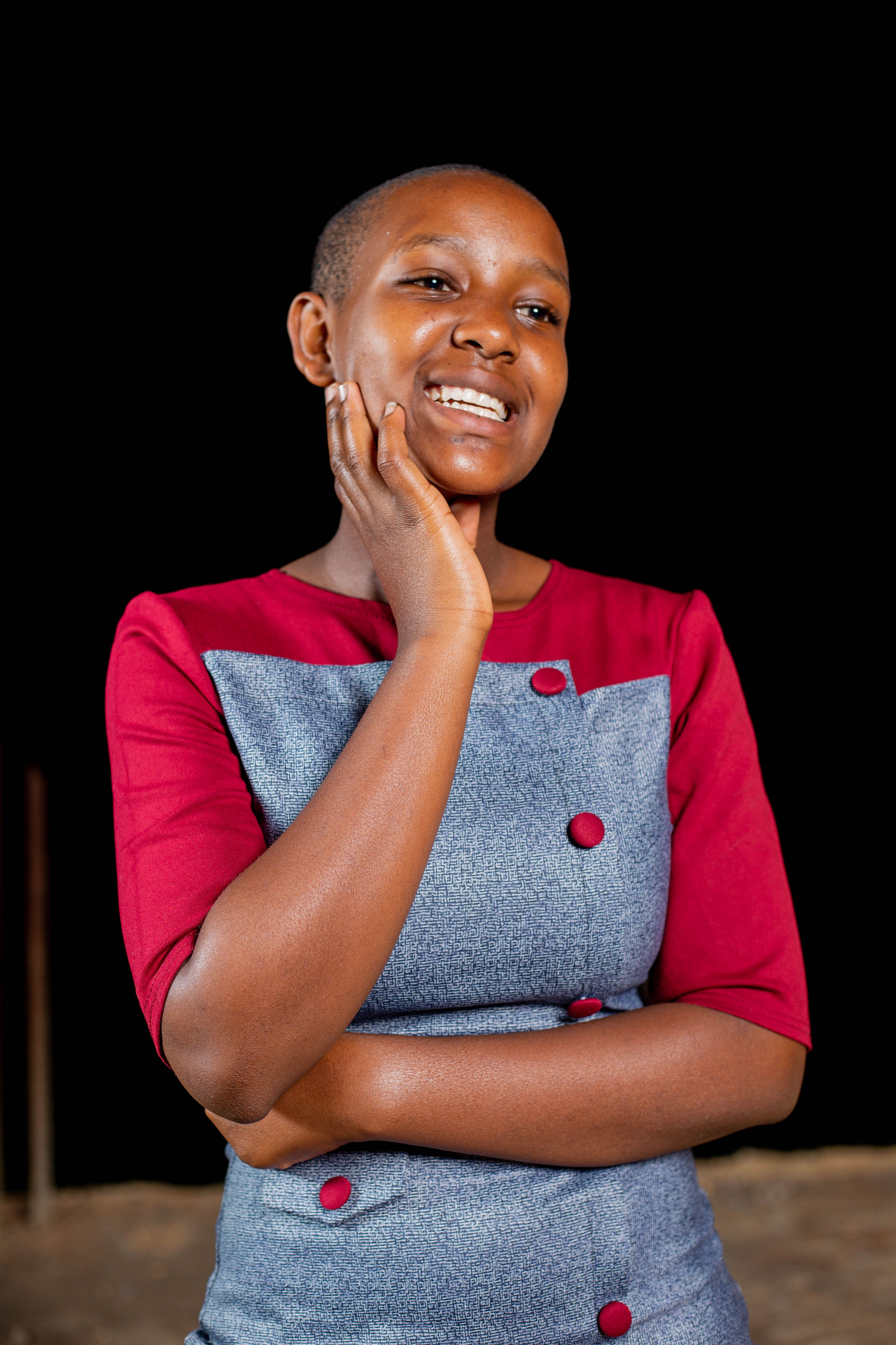 Portrait of a smiling woman in a stylish dress posing against a black background.