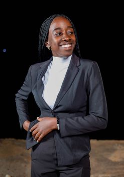 A confident businesswoman smiling, dressed in formal attire against a dark background.