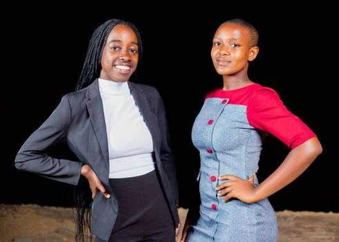 Confident young women in stylish business attire posing against a black background.
