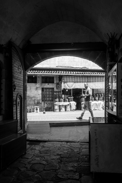 Free Black and white image captures a man walking in a traditional market passage. Stock Photo