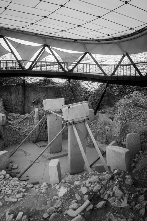 Free Black and white image of Göbekli Tepe's ancient stone pillars under a protective canopy. Stock Photo