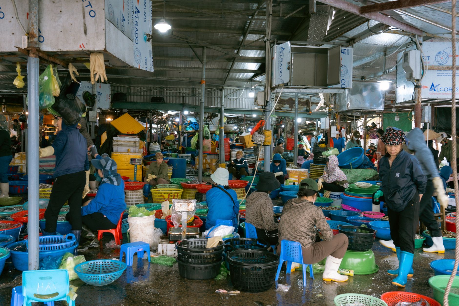 Lively indoor fish market in Vietnam with vendors and colorful baskets displaying fresh seafood.