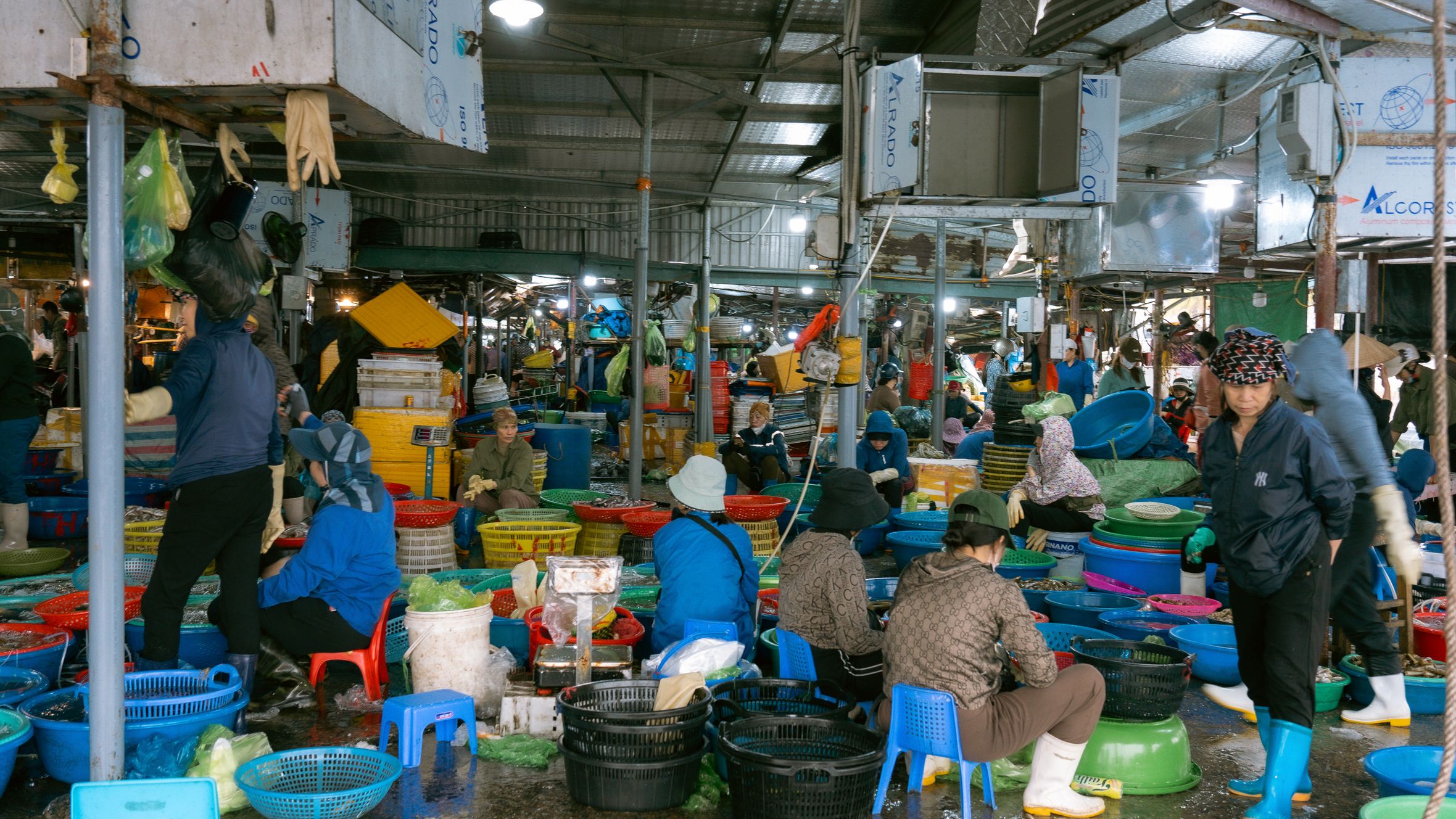 Lively indoor fish market in Vietnam with vendors and colorful baskets displaying fresh seafood.