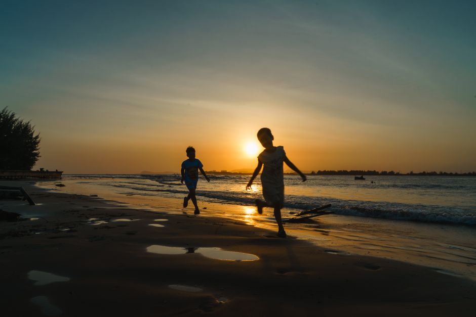 Two children joyfully playing on the beach during a beautiful sunset in Vũng Tàu, Vietnam.