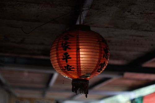 Free Close-up of a traditional red Chinese lantern hanging indoors, featuring cultural Chinese calligraphy. Stock Photo