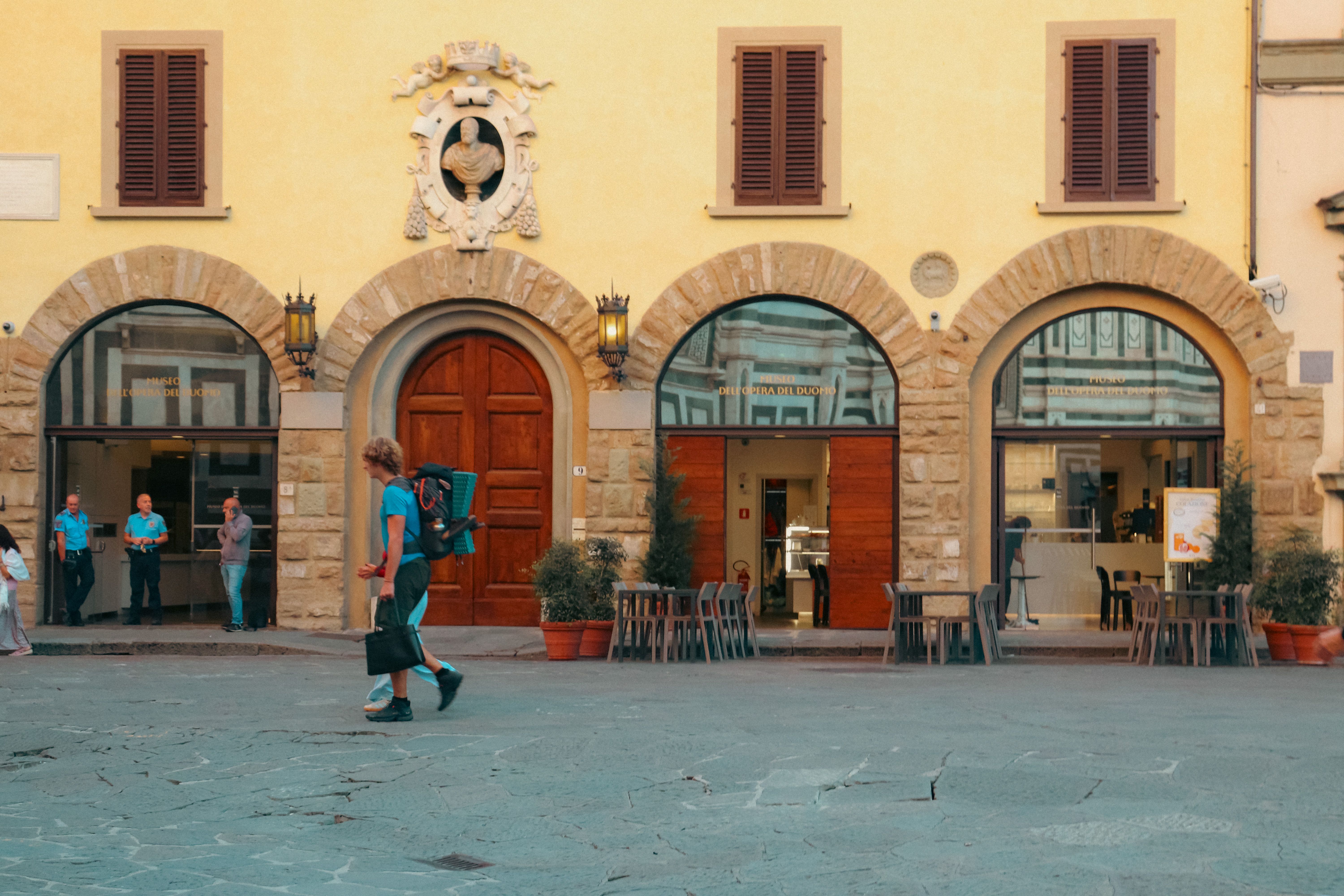 A vibrant scene in a Florentine piazza with people walking and historic architecture.