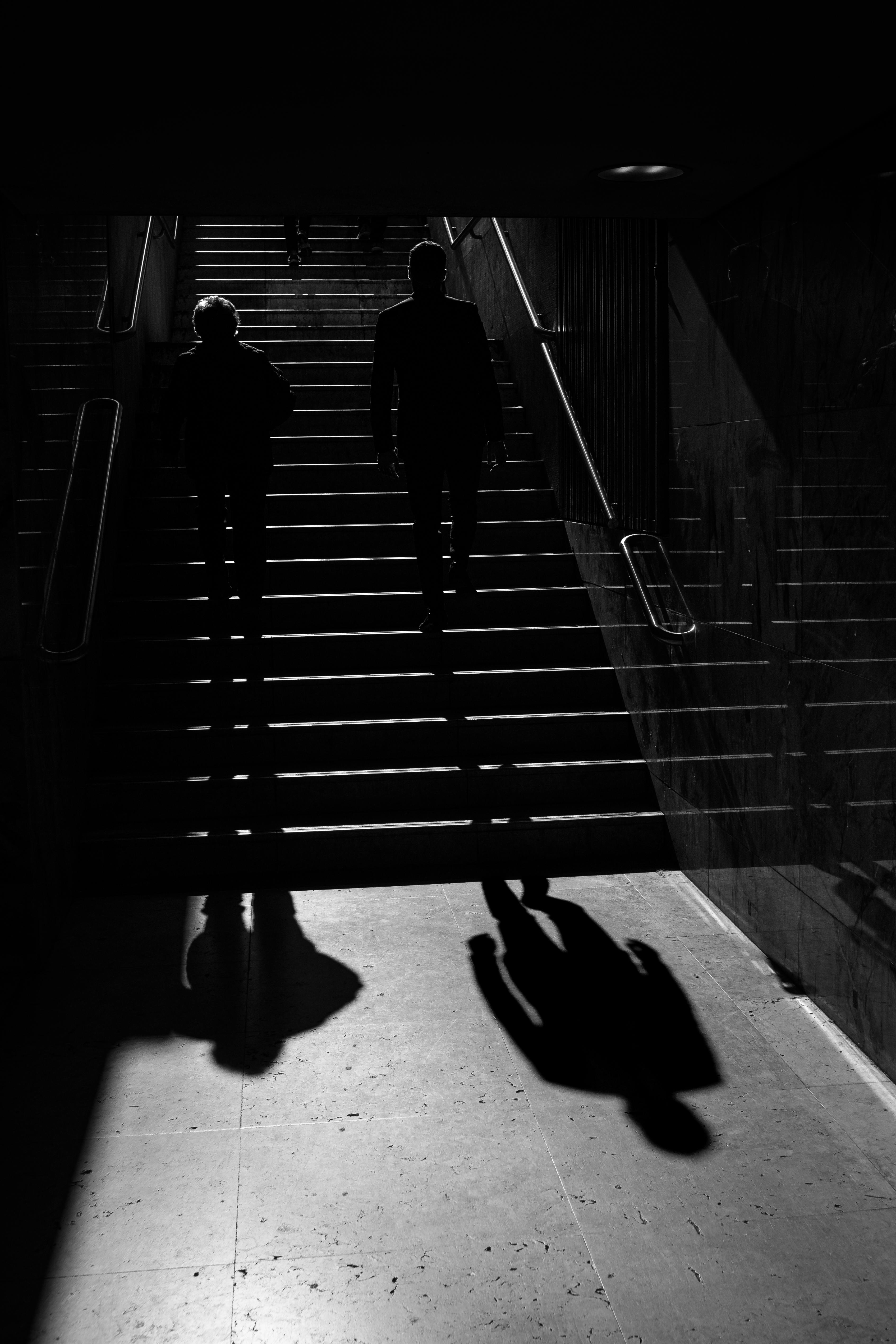 Dramatic black and white photo of silhouetted people on a city staircase in Lisbon.