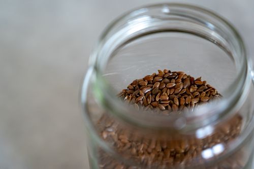 Free A clear glass jar filled with brown flax seeds, perfect for healthy cooking and baking. Stock Photo