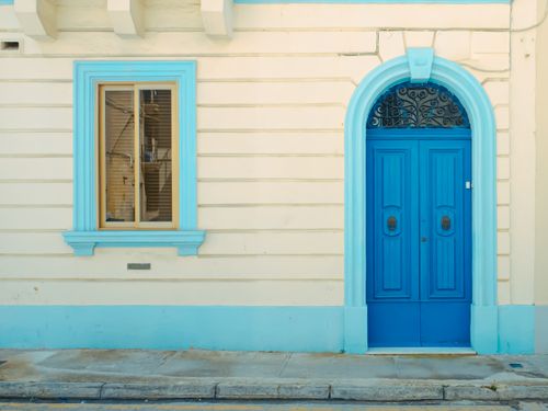 Free A striking blue door and window frame enhance the charm of colonial-style architecture in a cobbled street setting. Stock Photo