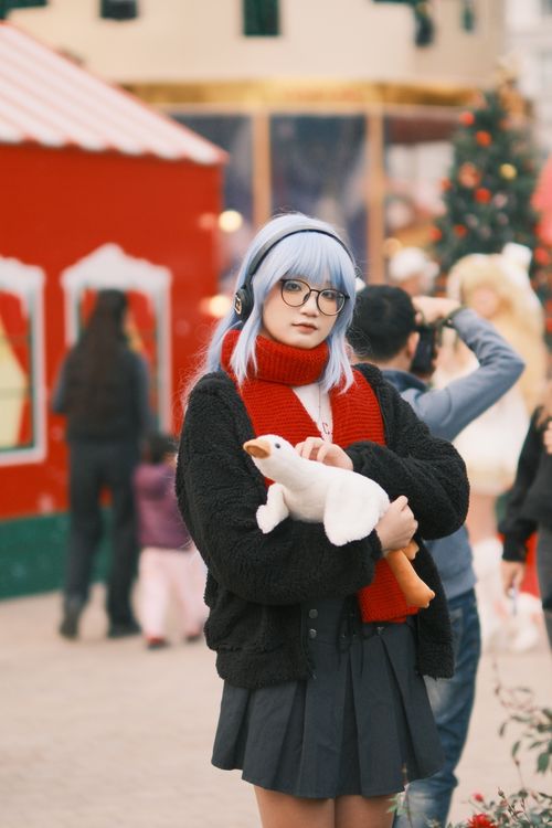 Free Young woman with blue hair, glasses, wearing winter clothing, holding a stuffed toy in a festive setting in Vietnam. Stock Photo