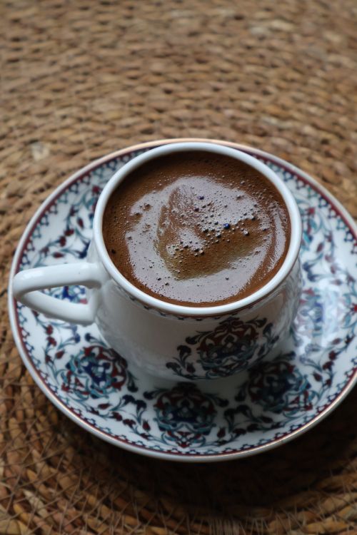 Free A close-up of Turkish coffee served in a decorative cup on a woven mat, showcasing cultural elegance. Stock Photo
