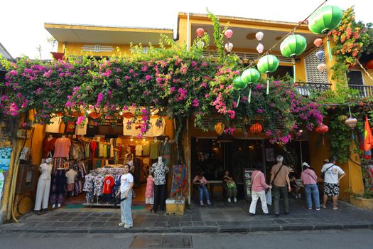 Charming street shop in Hội An with colorful lanterns and bougainvillea in a vibrant setting.