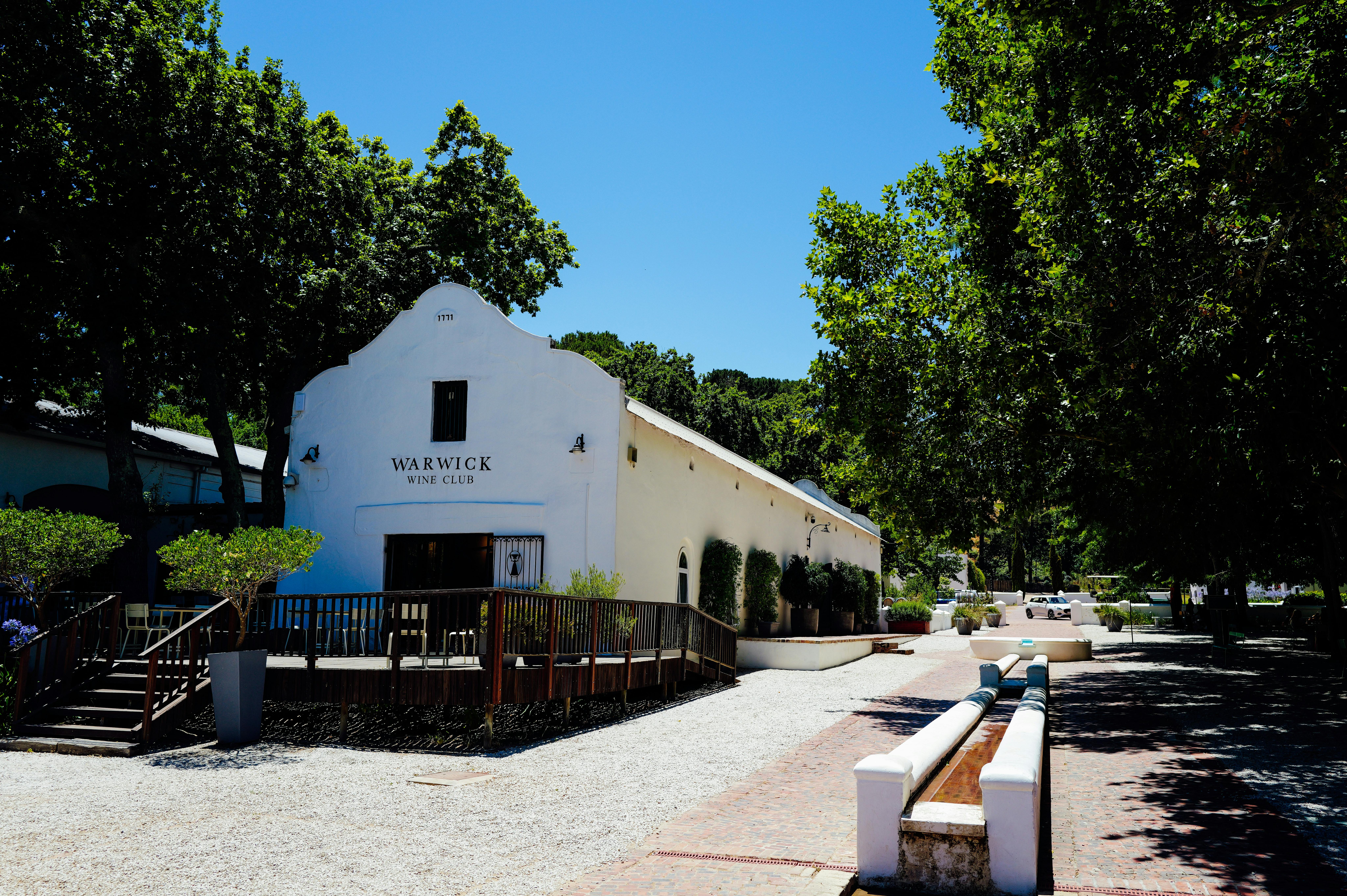 A picturesque view of Warwick Wine Club amidst lush greenery and blue skies.