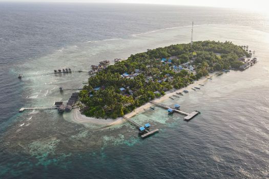 A breathtaking aerial view of a lush tropical island surrounded by blue ocean waters in Indonesia.