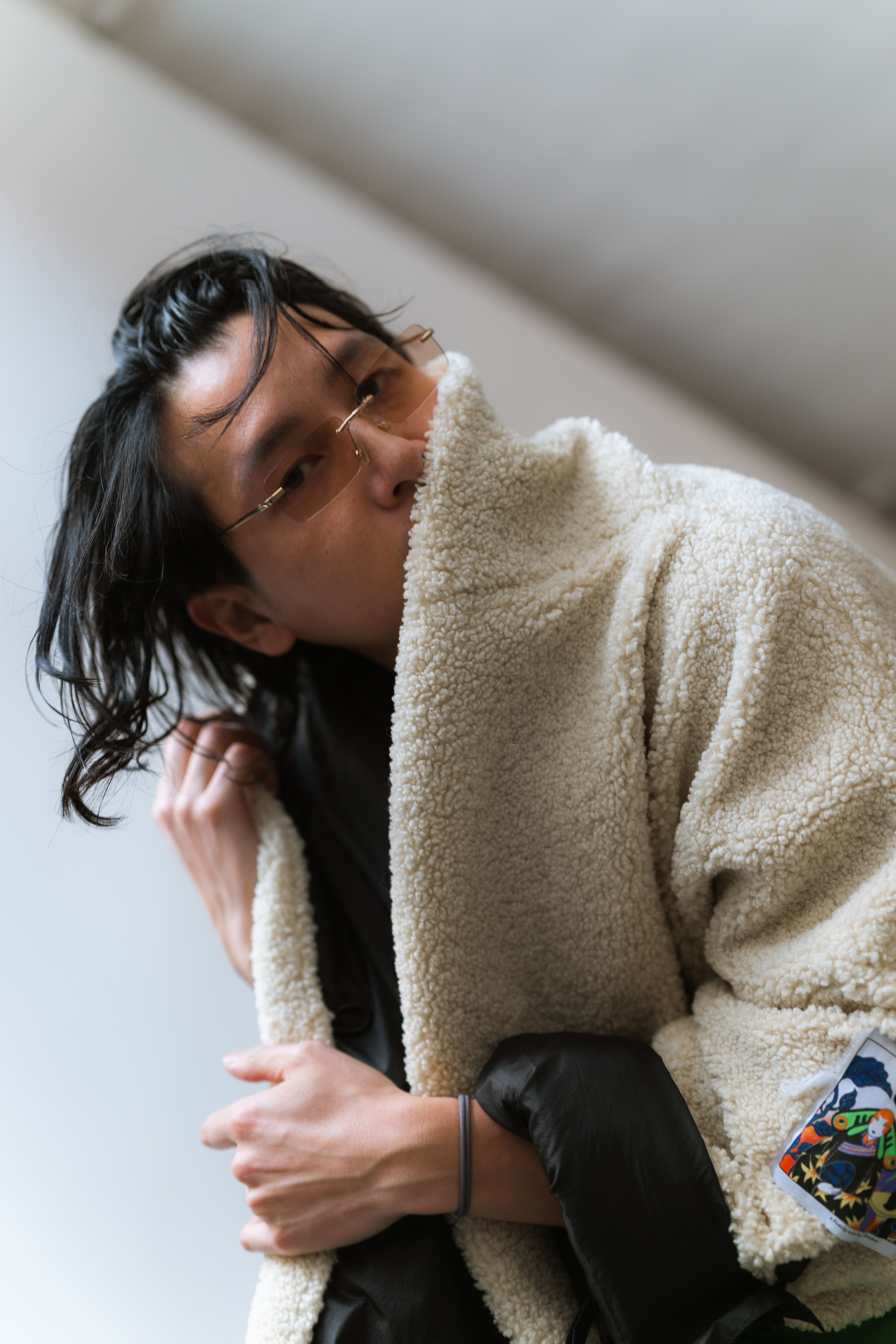 Young adult wearing a trendy fleece coat, showcasing winter style indoors.