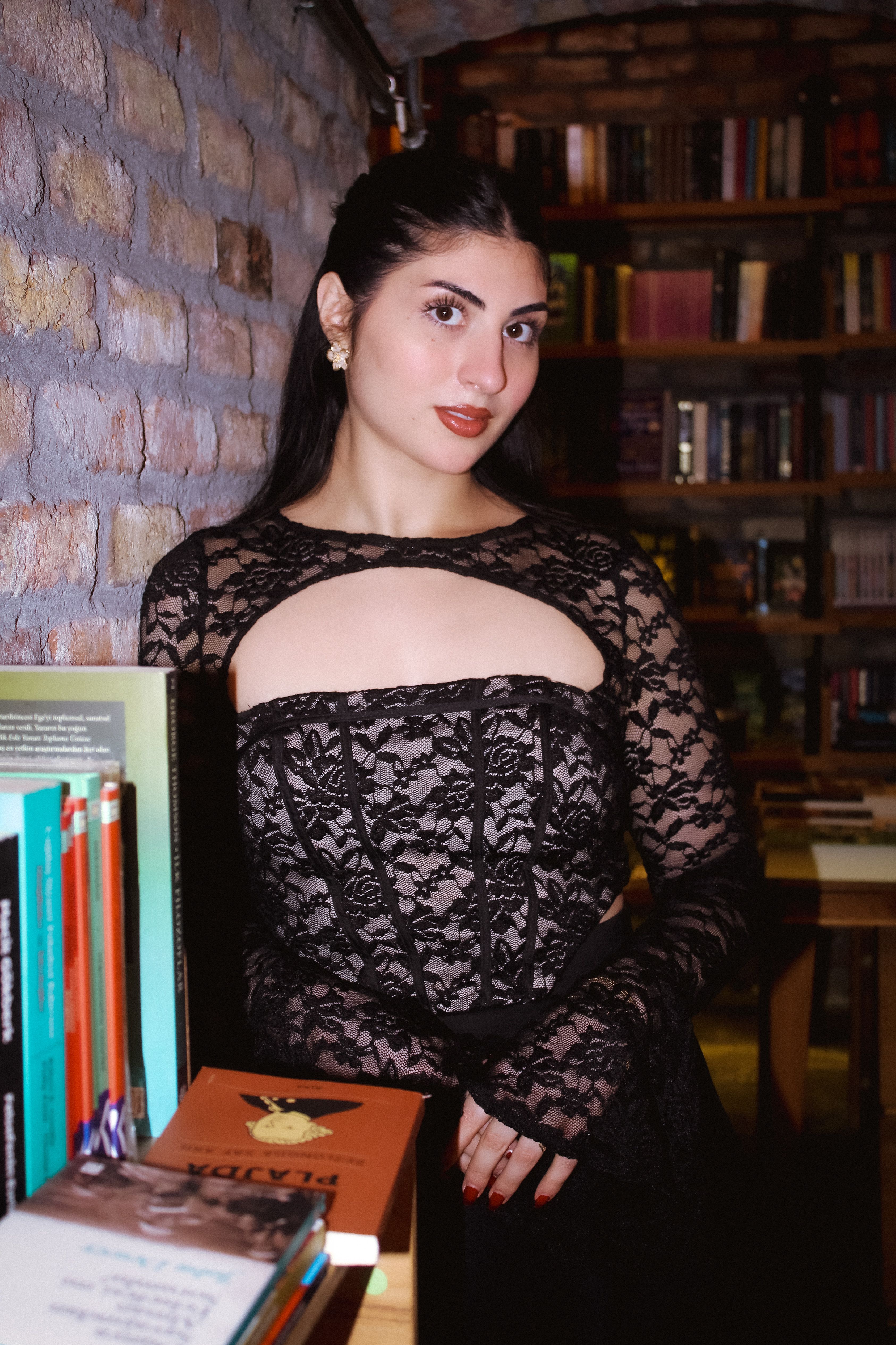 Elegant woman in a black lace dress in a cozy library ambiance.