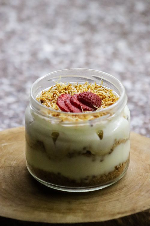 Free Delicious layered dessert in a jar topped with sliced strawberries and shredded coconut. Stock Photo