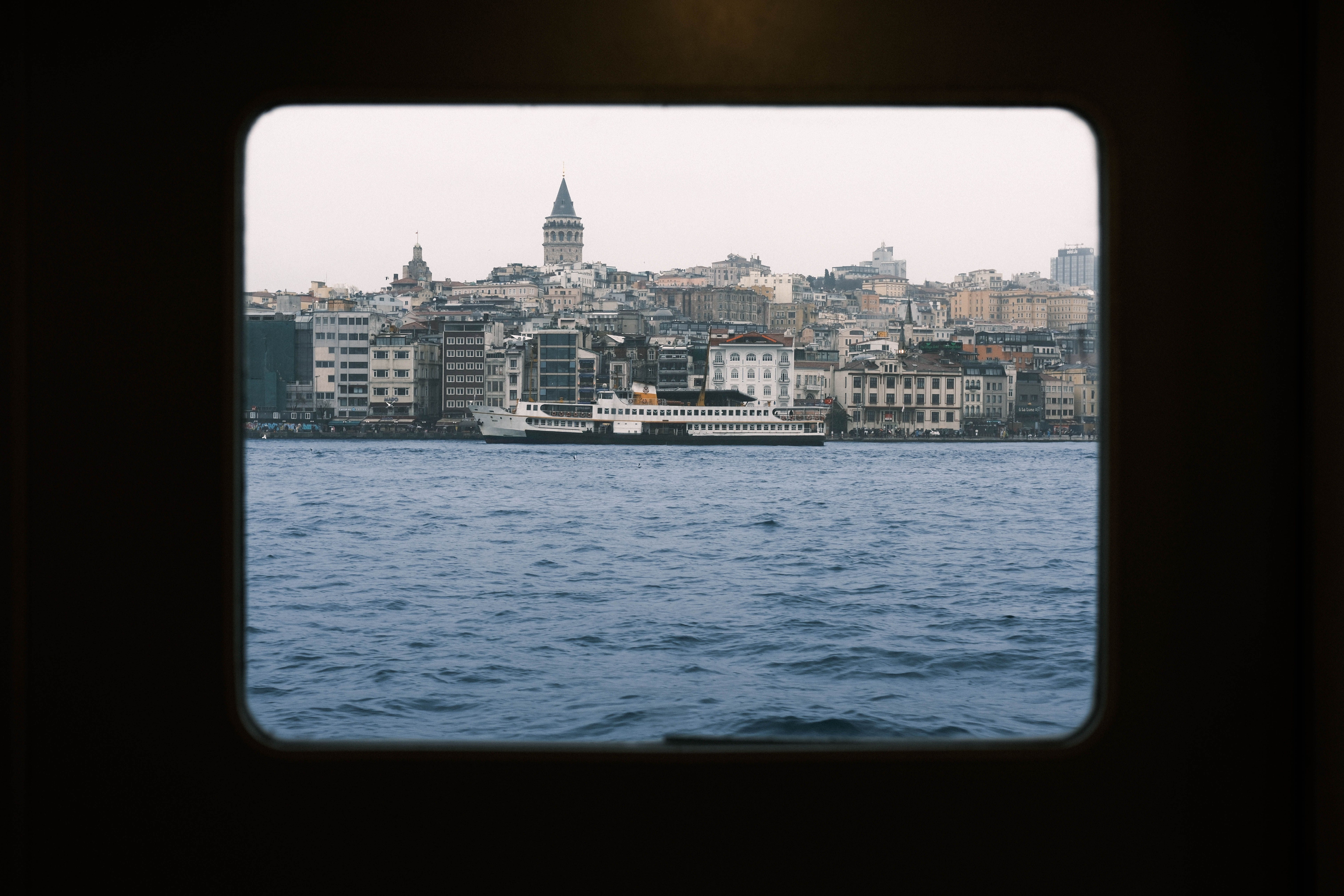 A public ferry crossing the Bosphorus in Istanbul with the Galata Tower and city skyline behind it