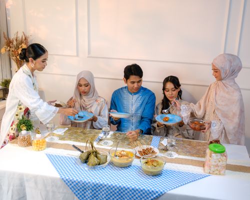 Free A joyful family enjoying a traditional iftar meal in Jakarta, dressed in cultural attire. Stock Photo