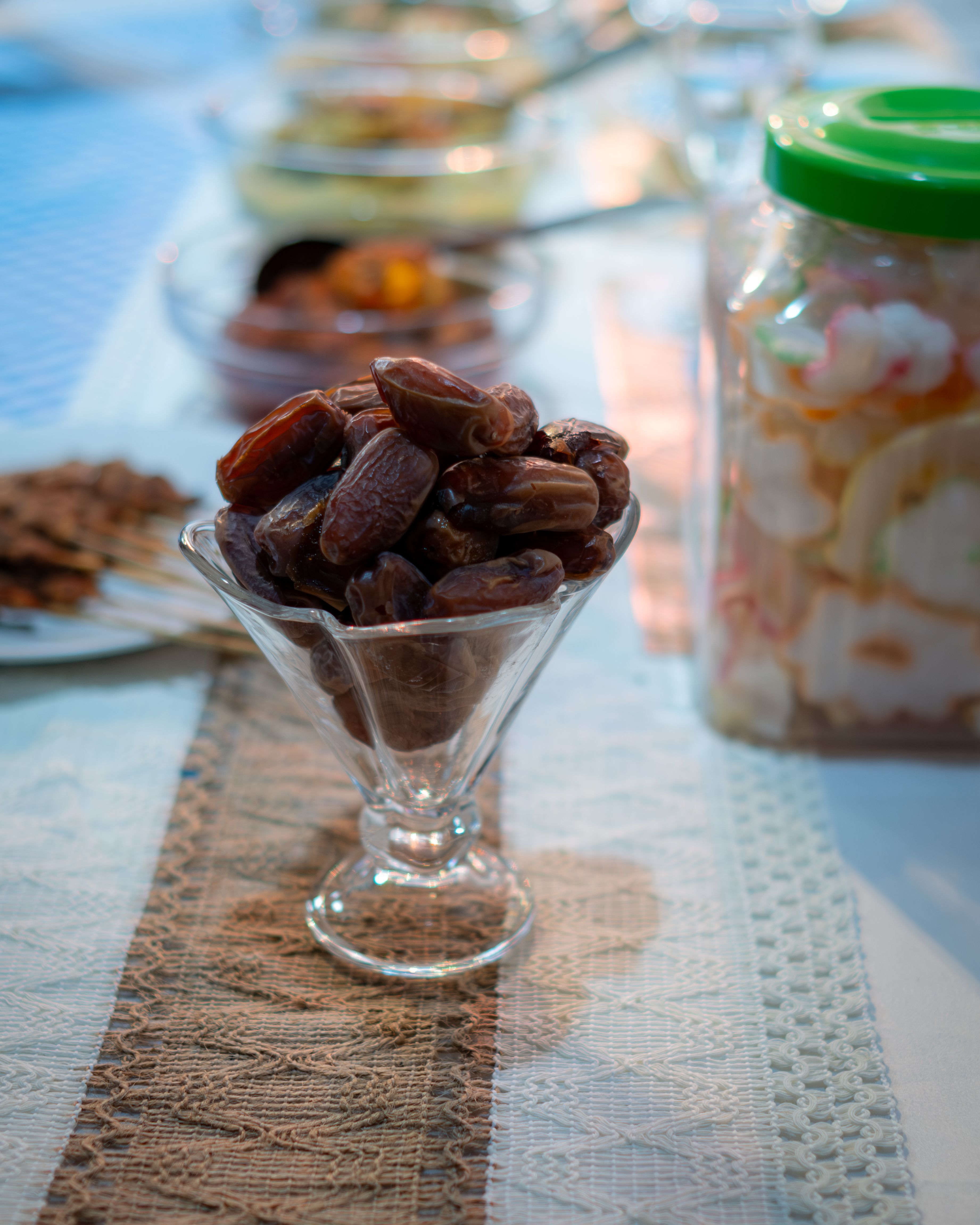 A glass bowl filled with dates on a decorated table, perfect for festive occasions or Ramadan.