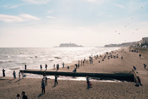 Free People enjoy a sunny day at the beach with waves crashing and a distant island on the horizon. Stock Photo
