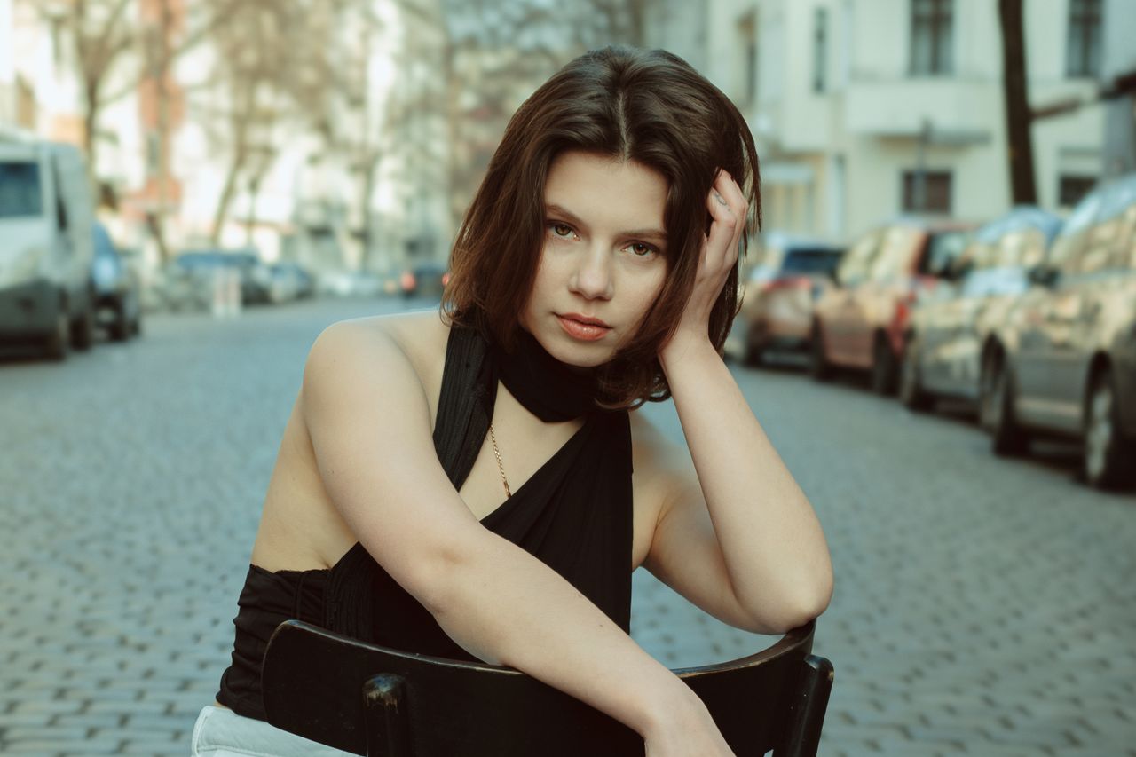 elegant portrait of a young woman seated on a berlin street with styli