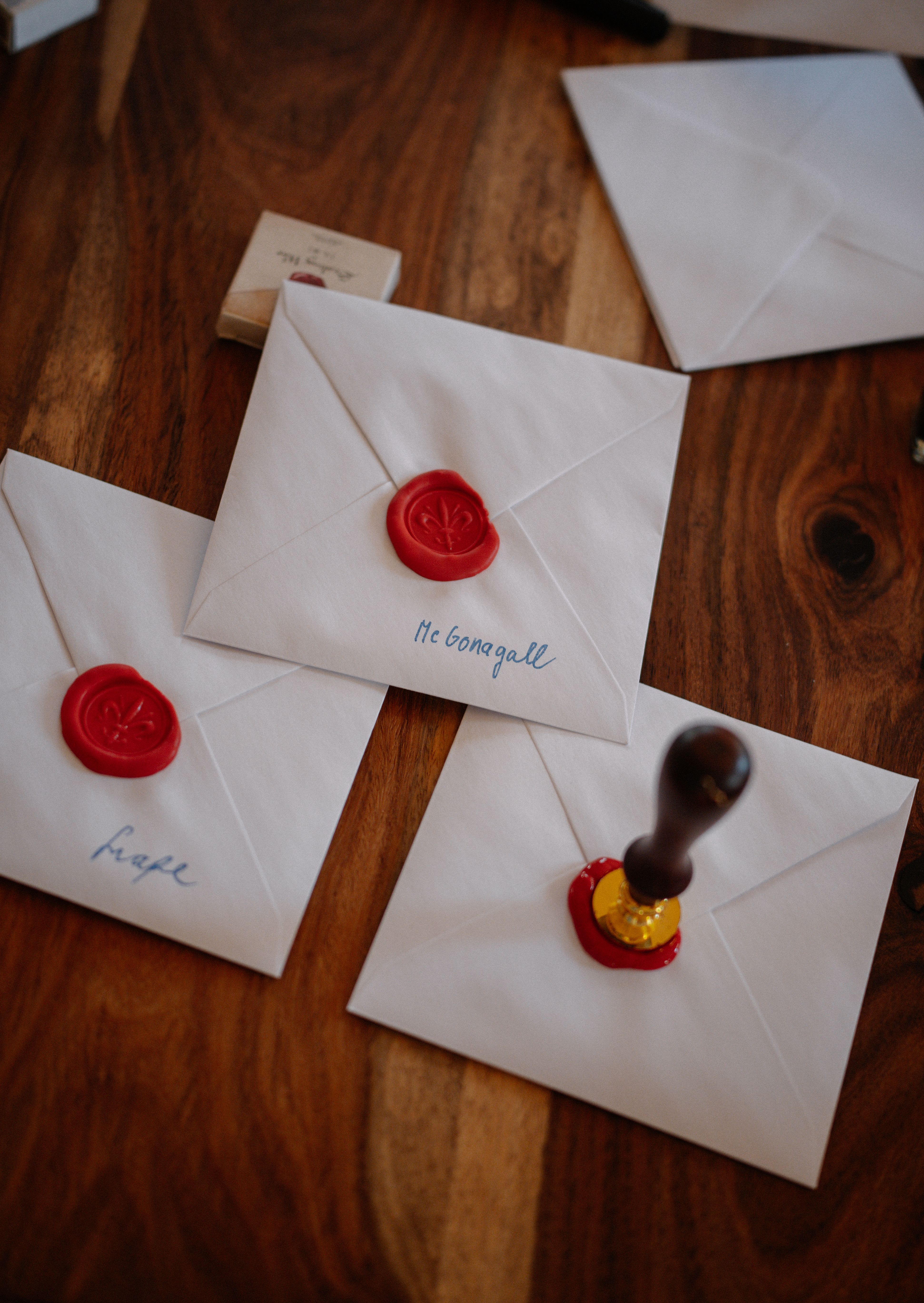 Elegant white envelopes sealed with wax on a wooden table, perfect for invitations.
