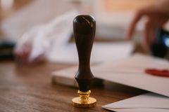 A close-up of a vintage wax seal stamp on a wooden desk with envelopes, conveying an old-world charm.