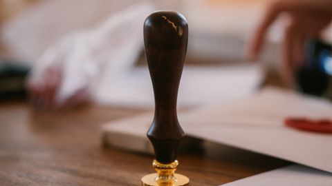 A close-up of a vintage wax seal stamp on a wooden desk with envelopes, conveying an old-world charm.