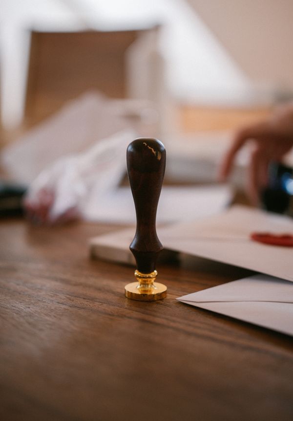 A brass wax seal stamp resting on a writing desk — photo by Raymond Petrik on Pexels