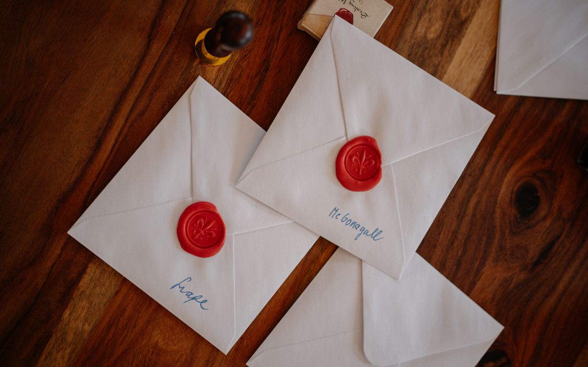 Three white envelopes sealed with red wax are creatively displayed on a wooden table, suggesting a vintage theme.