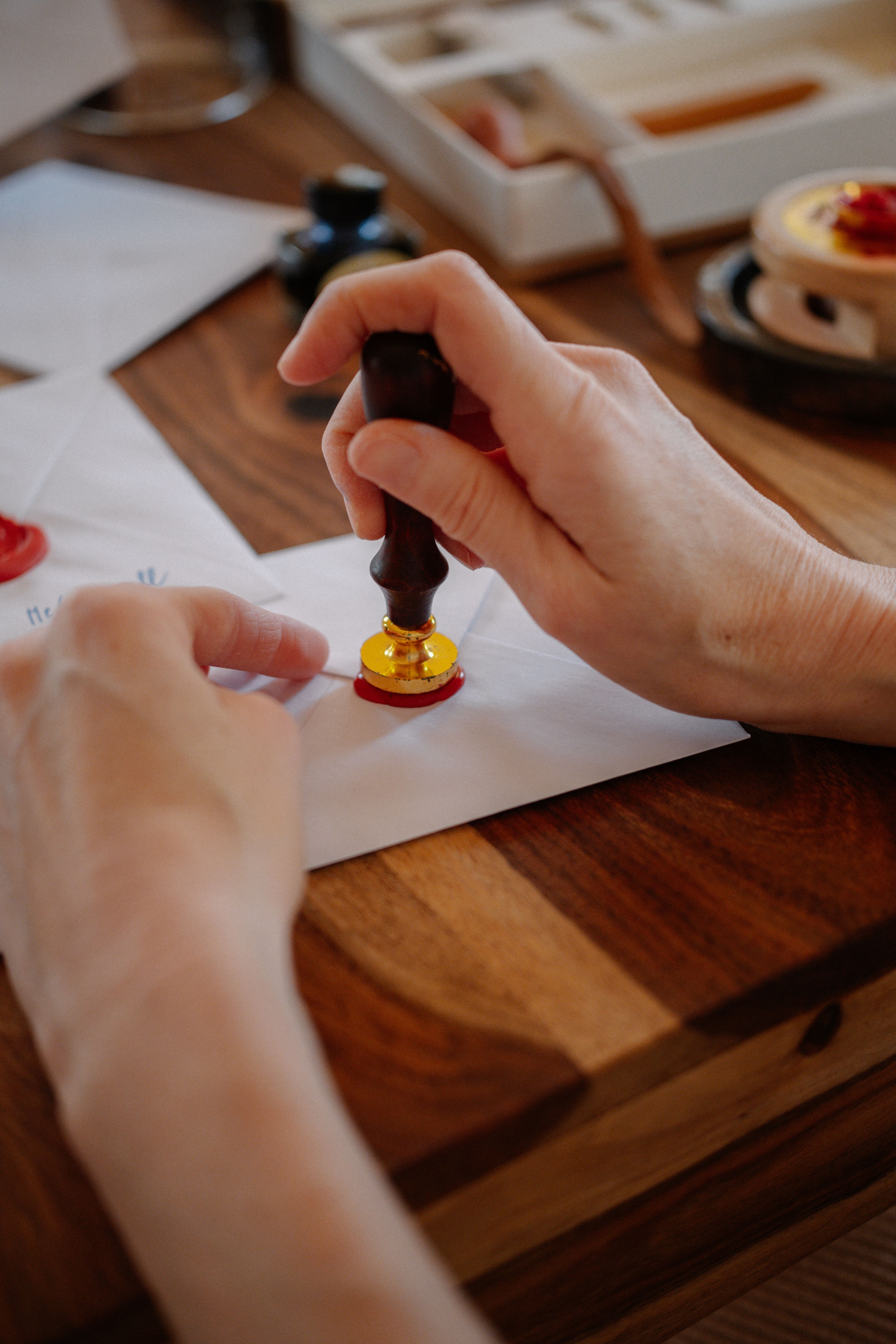 A person sealing an envelope with a wax stamp on a wooden table, creating a vintage feel.