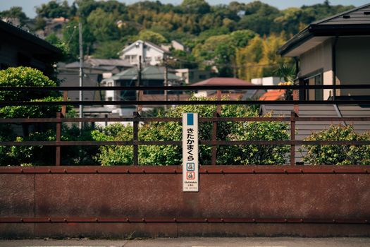 A sign at Kita Kamakura station, surrounded by lush greenery, under a clear sky in Japan.