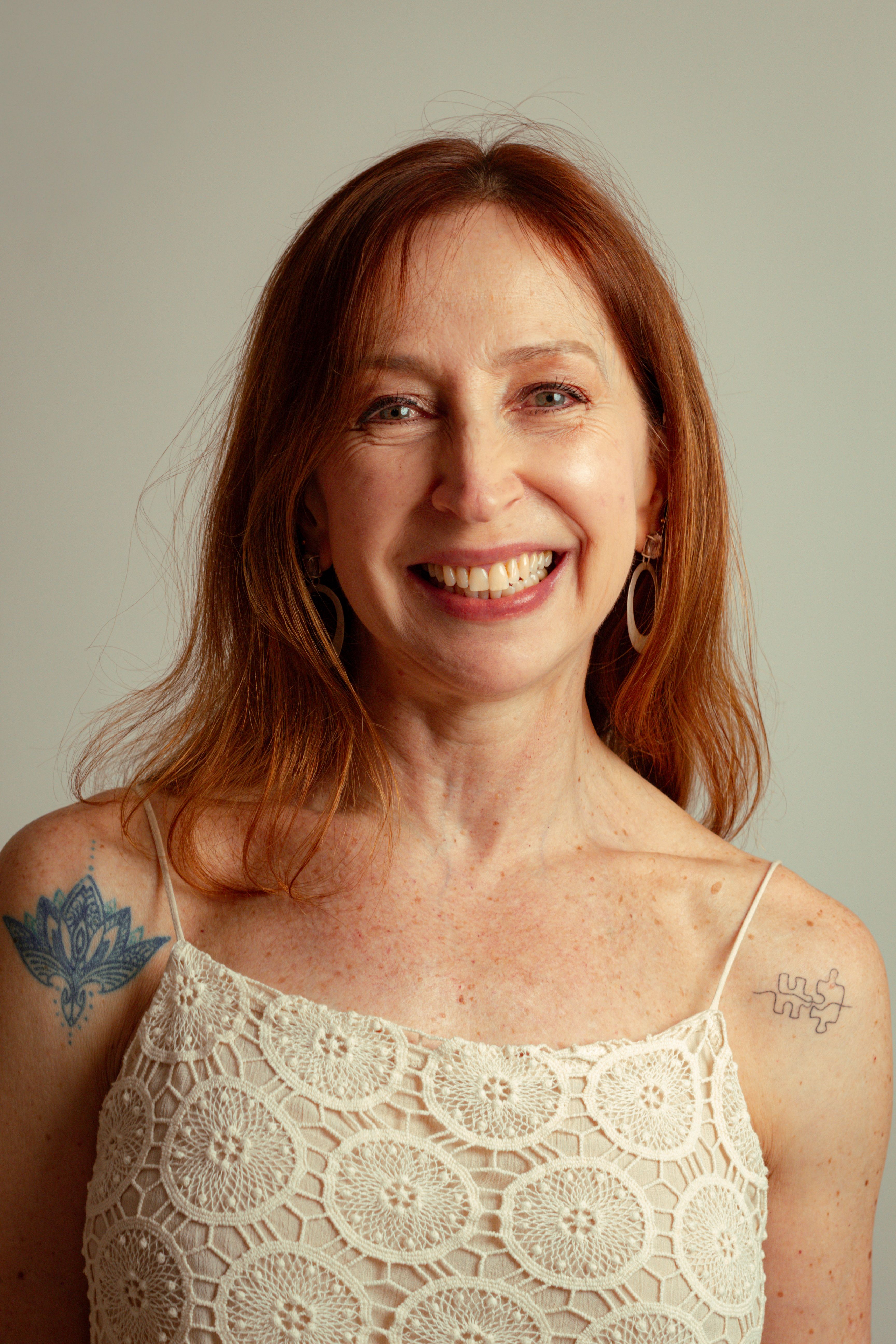 Portrait of a smiling woman with ginger hair and tattoos in São Paulo.