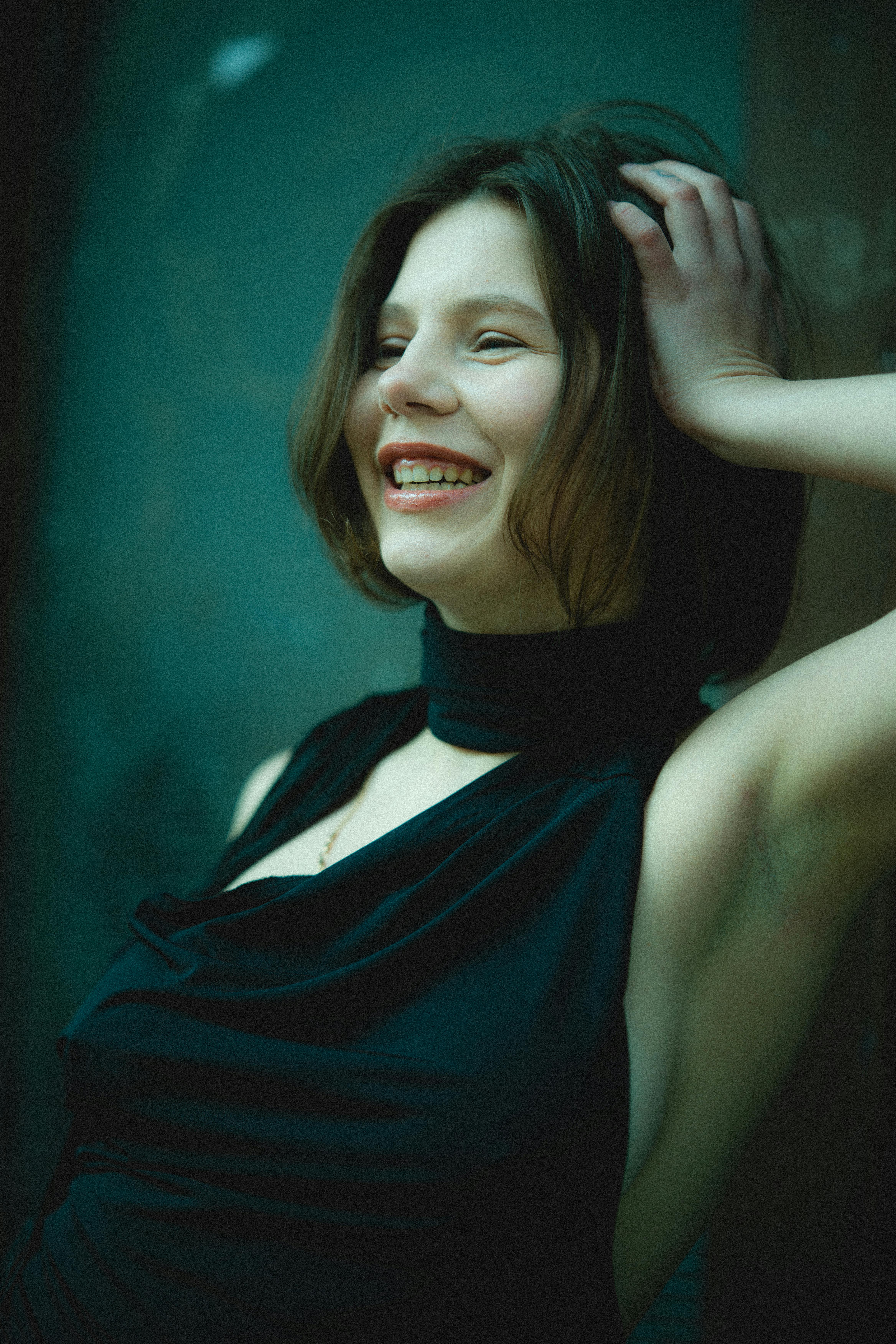 Portrait of a joyful young woman in an elegant black dress, smiling with natural beauty.