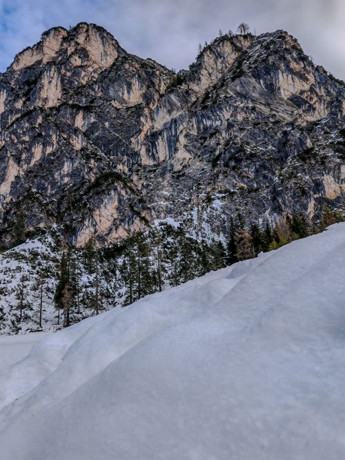 Free Breathtaking view of a snow-covered mountain with rocky peaks and forested slopes. Stock Photo