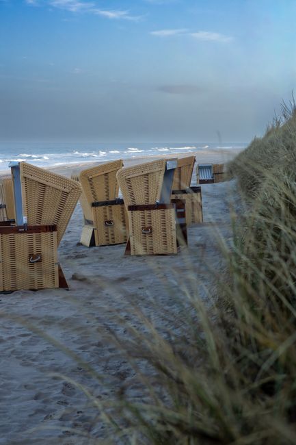 A quiet beach campsite with a tent near dunes and gentle waves at sunrise