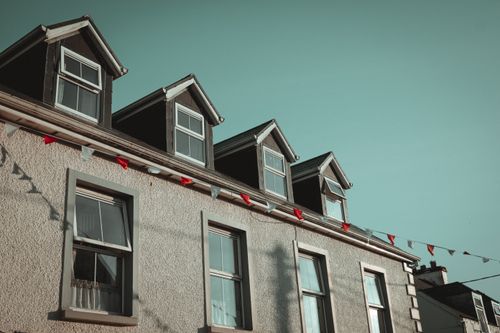 Free Quaint residential building with dormer windows and decorative bunting under clear skies. Stock Photo