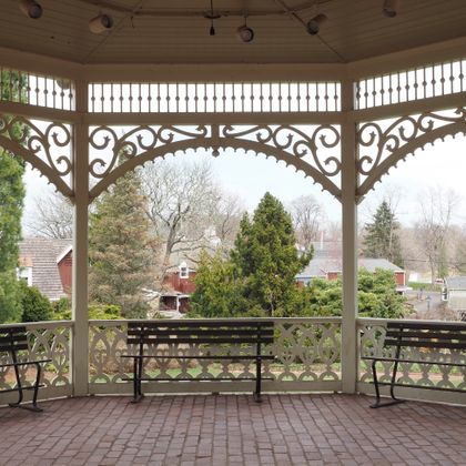 View from inside a wooden village gazebo over rooftops and trees &mdash; Gene Samit on Pexels