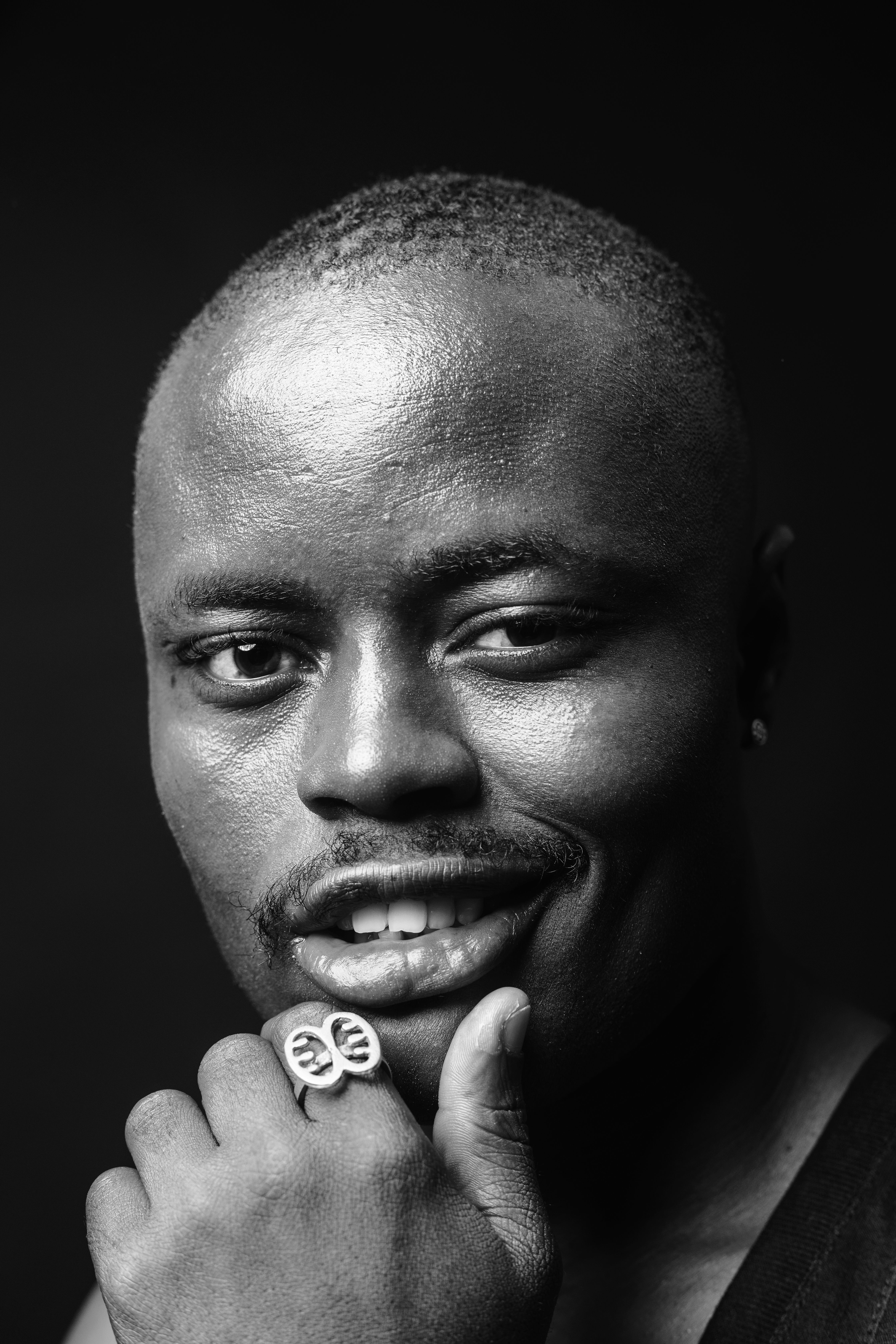 A captivating black and white portrait of a man with a thoughtful expression, wearing a ring.
