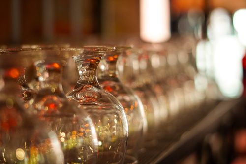 Free A row of clear upside-down wine glasses with a warm bokeh background, creating a cozy ambiance. Stock Photo