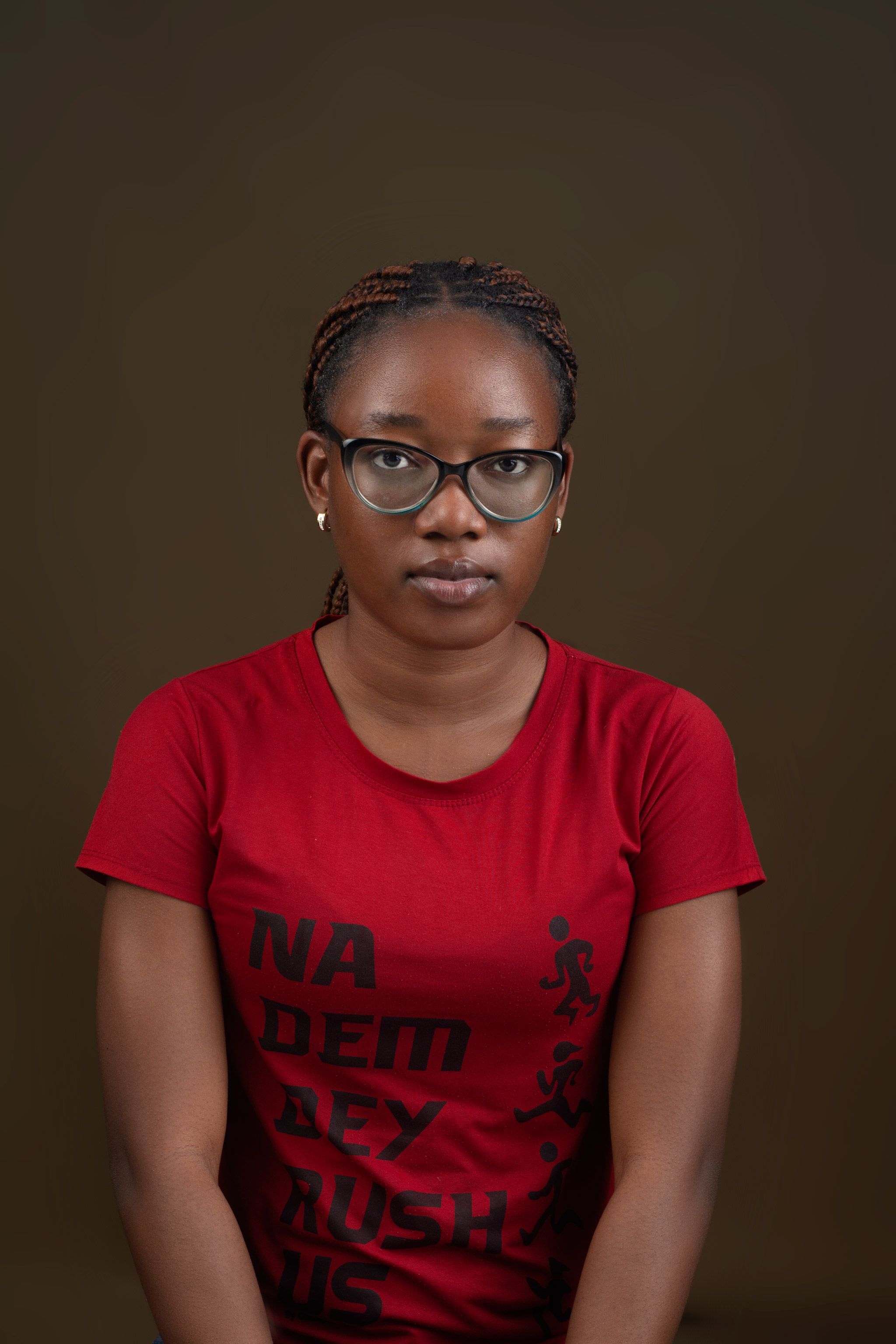 A young adult wearing glasses and a red shirt in a studio portrait.