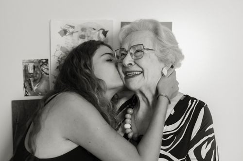 Free A touching moment of a young woman embracing and kissing an elderly woman indoors. Stock Photo