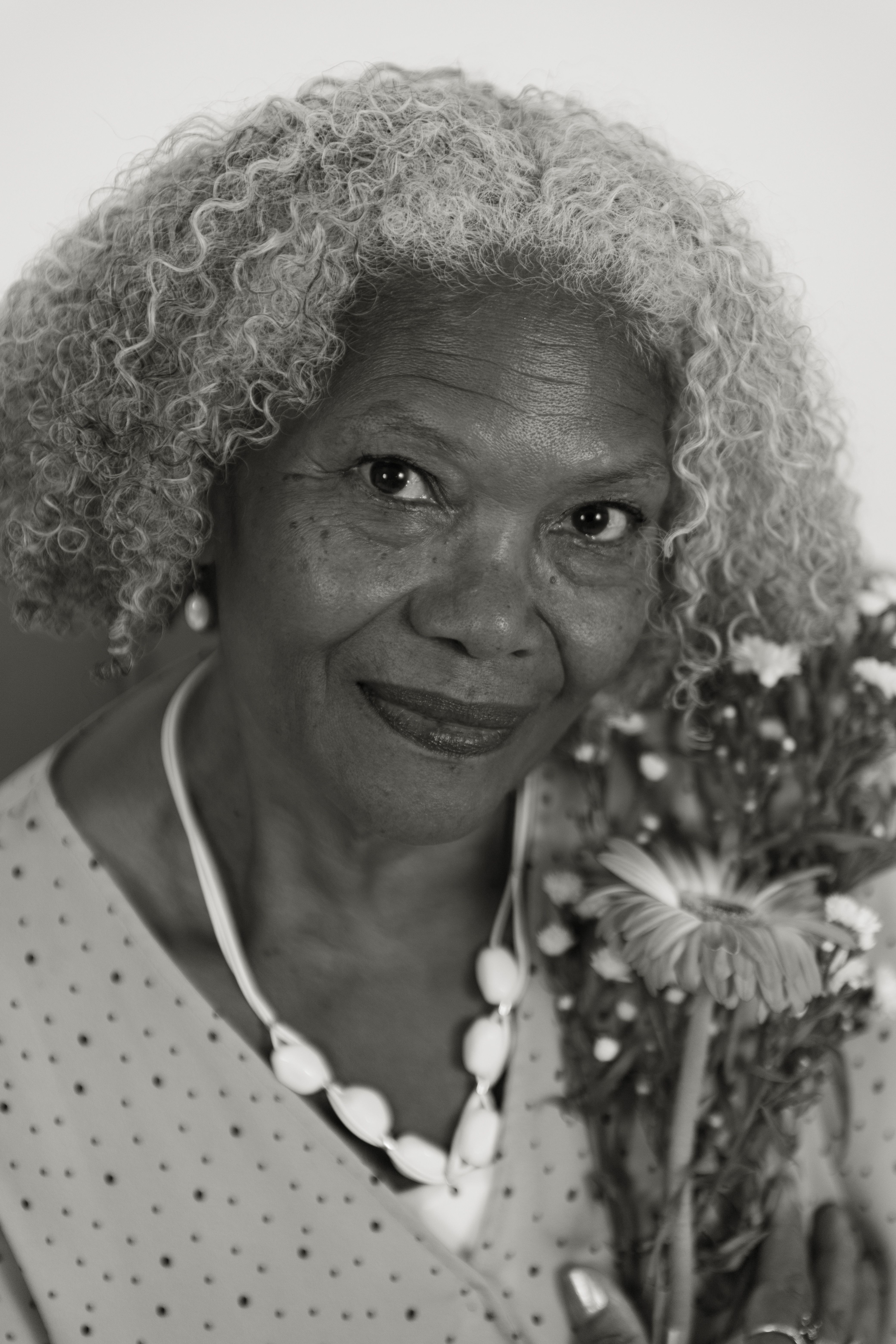 Elegant black and white portrait of a senior woman holding flowers, exuding warmth and wisdom.