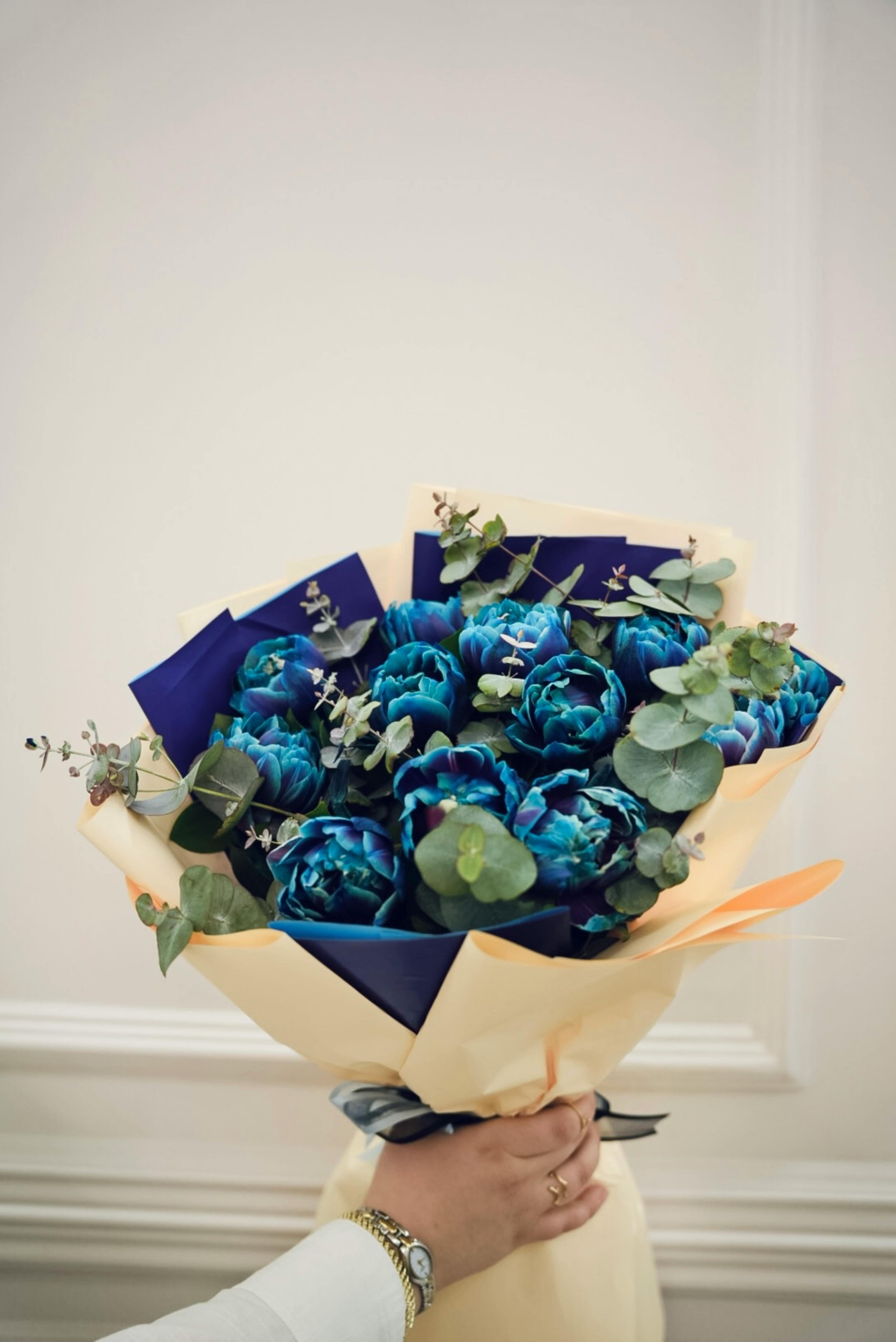 [ColoSach]-a-beautiful-bouquet-of-blue-flowers-elegantly-wrapped,-held-by-a-hand-with-a-bracelet.
